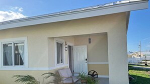 Een gelijkvloers huis met een overdekte veranda, een deur en een raam.