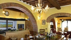 A dining area with a long wooden table, chairs, a chandelier, and a brick archway.