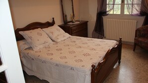 Un dormitorio con una cama de madera, una mesita de noche, un espejo, una silla y una ventana con cortinas.