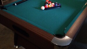 Una mesa de billar con superficie de fieltro verde, una bola blanca y un despliegue de bolas de billar.