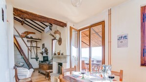 A dining area with a wooden table set for two, a fireplace, and a view through large windows. - Villa in Cortona With Pool (Cortona)