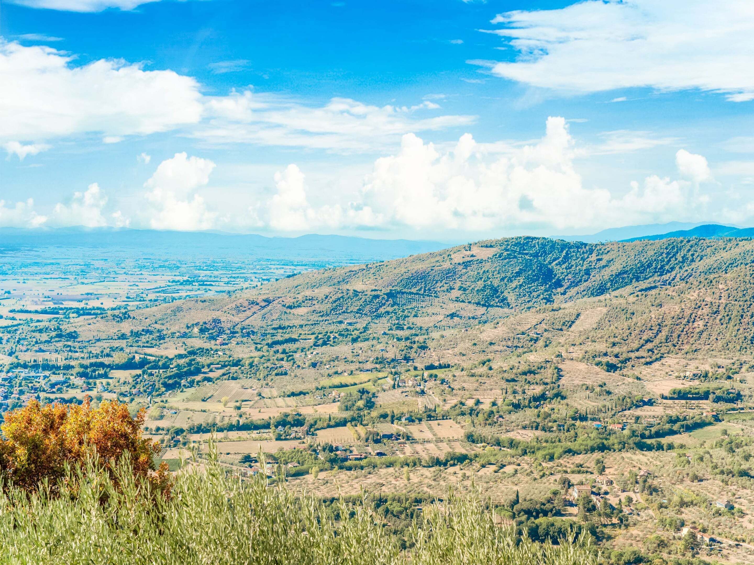 A panoramic view of a hilly landscape with scattered buildings, likely a rural area.