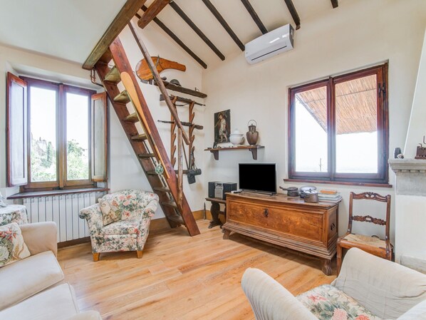 A room with wooden floors, a wooden staircase, a television, and a fireplace. - Villa in Cortona With Pool (Cortona)