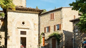A narrow stone street with buildings featuring arched doorways and wooden shutters. - Villa in Cortona With Pool (Cortona)