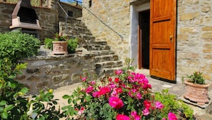 Un bâtiment en pierre avec une porte en bois, un escalier en pierre et un four en briques.