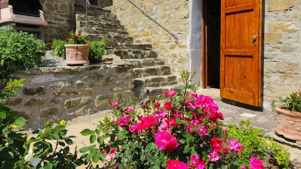 Un bâtiment en pierre avec une porte en bois, un escalier et des plantes en pot.