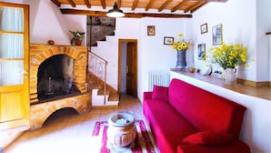 Un salon avec un canapé rouge, une cheminée, un escalier et un radiateur.