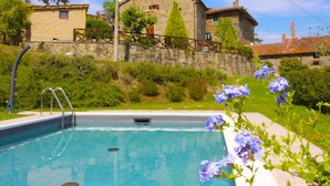 Une piscine avec une maison en pierre en arrière-plan.