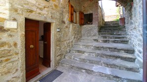Un escalier en pierre mène à une porte en bois ornée d’une plaque portant un numéro.