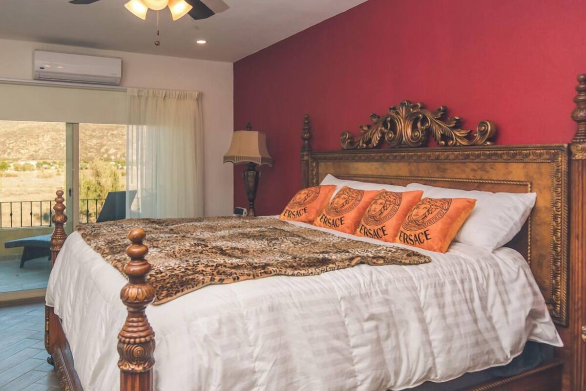 Une chambre avec un grand lit, une tête de lit en bois et une vue sur l’extérieur.