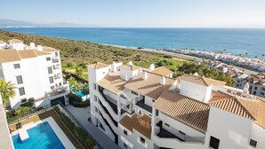 Un hotel sulla costa con piscina, numerosi balconi e vista mare.