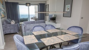 Un soggiorno moderno con un tavolo da pranzo in vetro, sedie blu e un divano.