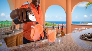 Um barman servindo uma bebida num copo com uma fatia de fruta.