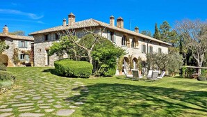 Una villa in pietra con un prato curato e un vialetto in pietra che conduce all'ingresso.