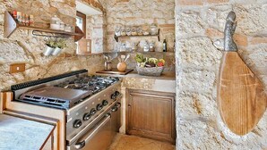 Una cucina rustica con pareti in pietra, travi in legno e un fornello.