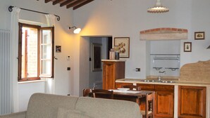 Una sala de estar acogedora con un sofá, una mesa de comedor y una zona de cocina con armarios de madera y un lavabo.