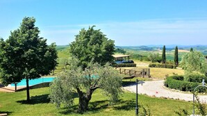 Un paisaje verde exuberante con un pabellón, un sendero y vistas a colinas distantes.