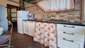 Cocina compacta con refrigerador, cafetera y estufa a gas.