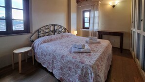 Un dormitorio con una cama, una mesita, una ventana y un radiador.