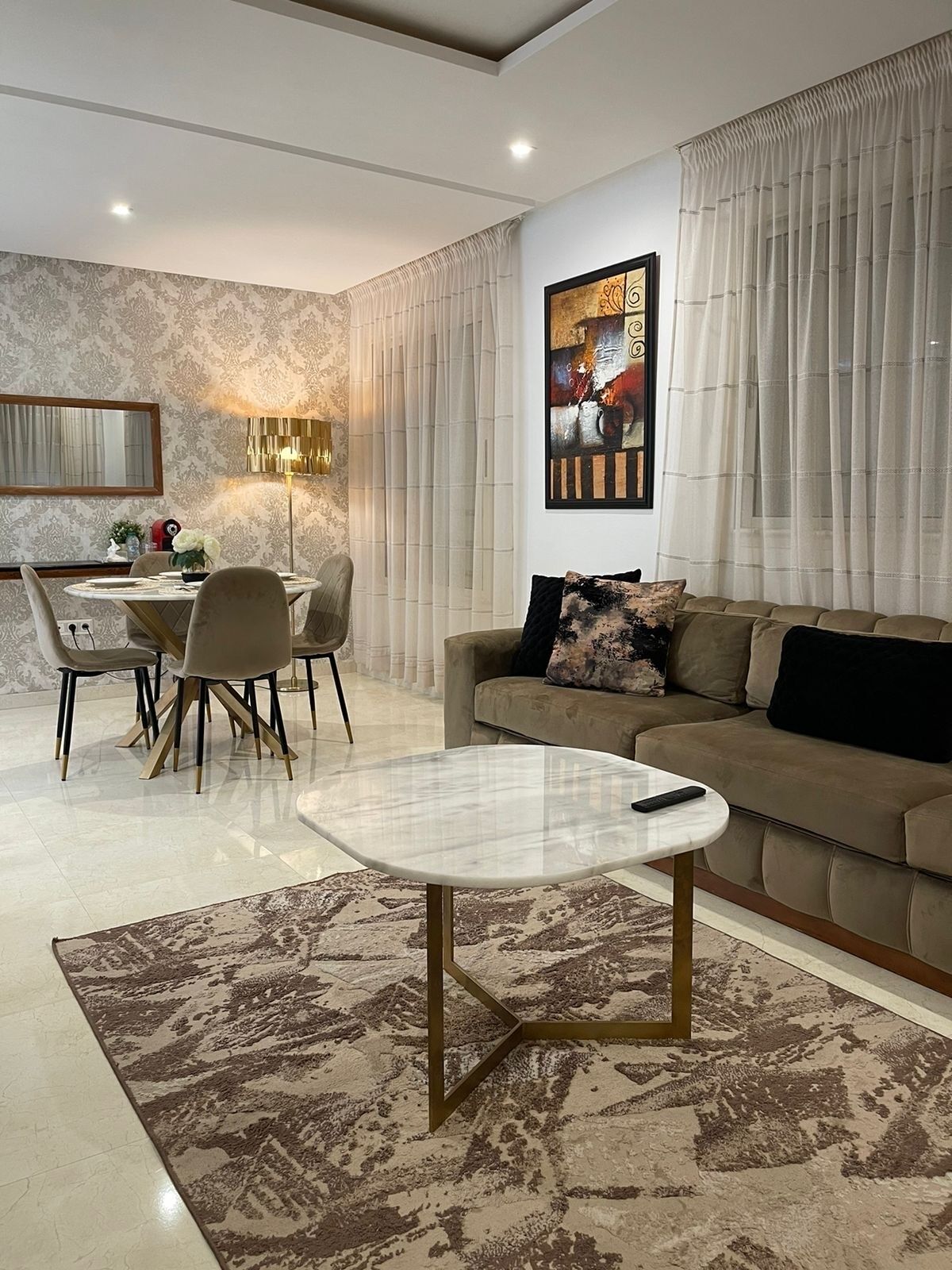 A modern living room with a sofa, a coffee table, and a dining area.