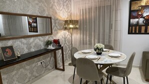 Un coin repas avec une table ronde, quatre chaises, un miroir, une lampe et un tableau accroché au mur.