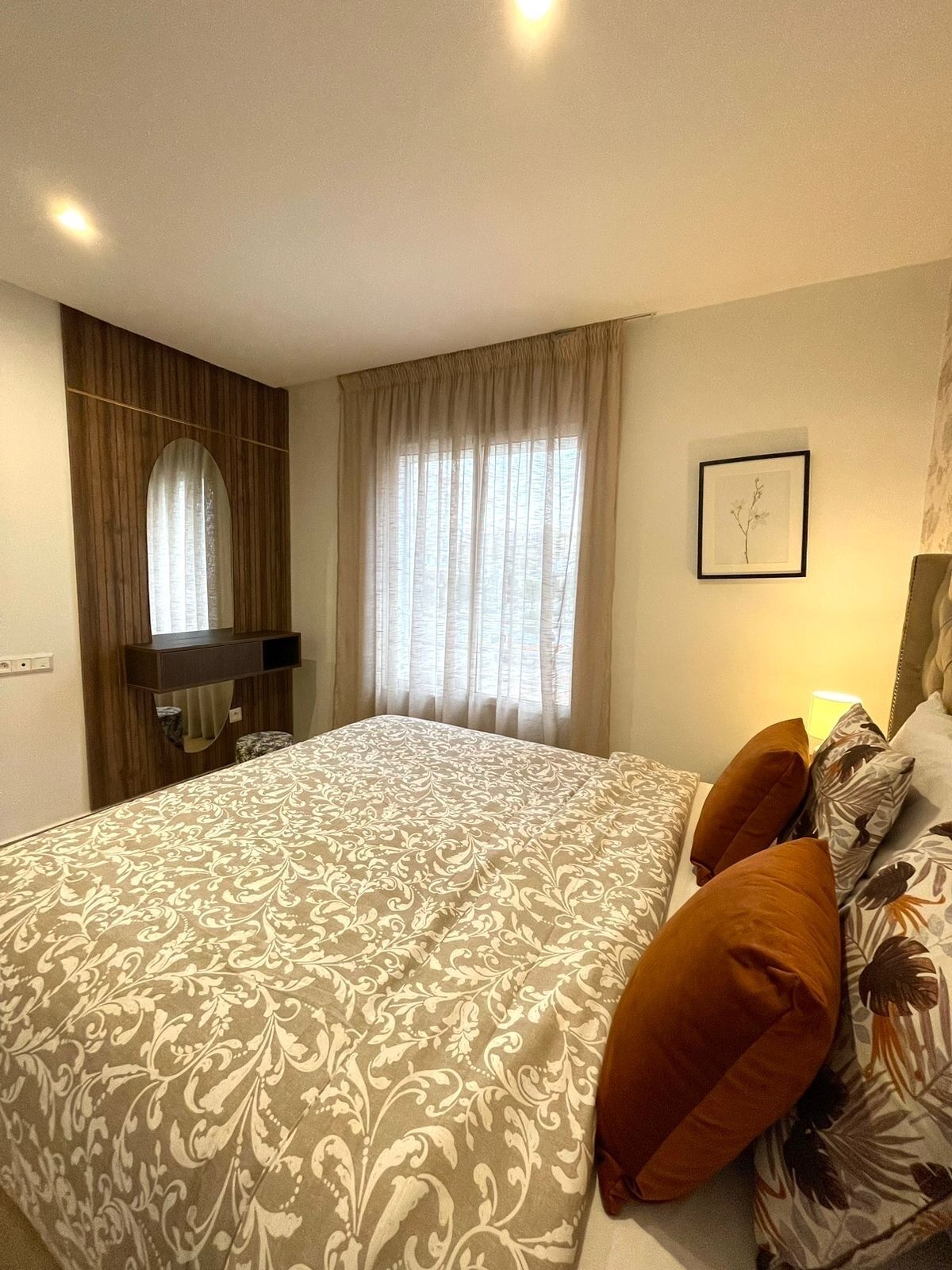 Ein Schlafzimmer mit einem großen Bett, einem Holzschrank, einem Schreibtisch und einem Fenster mit Vorhängen.