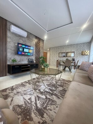 A modern living room with a flat-screen TV, a glass coffee table, a sofa, and a dining area. - Excellent apartment in the center of Oujda (Oujda)