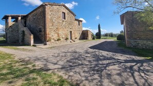 A stone building with a gravel driveway leading to a wooden door. - Tasteful Countryside Stay (Montalcino)