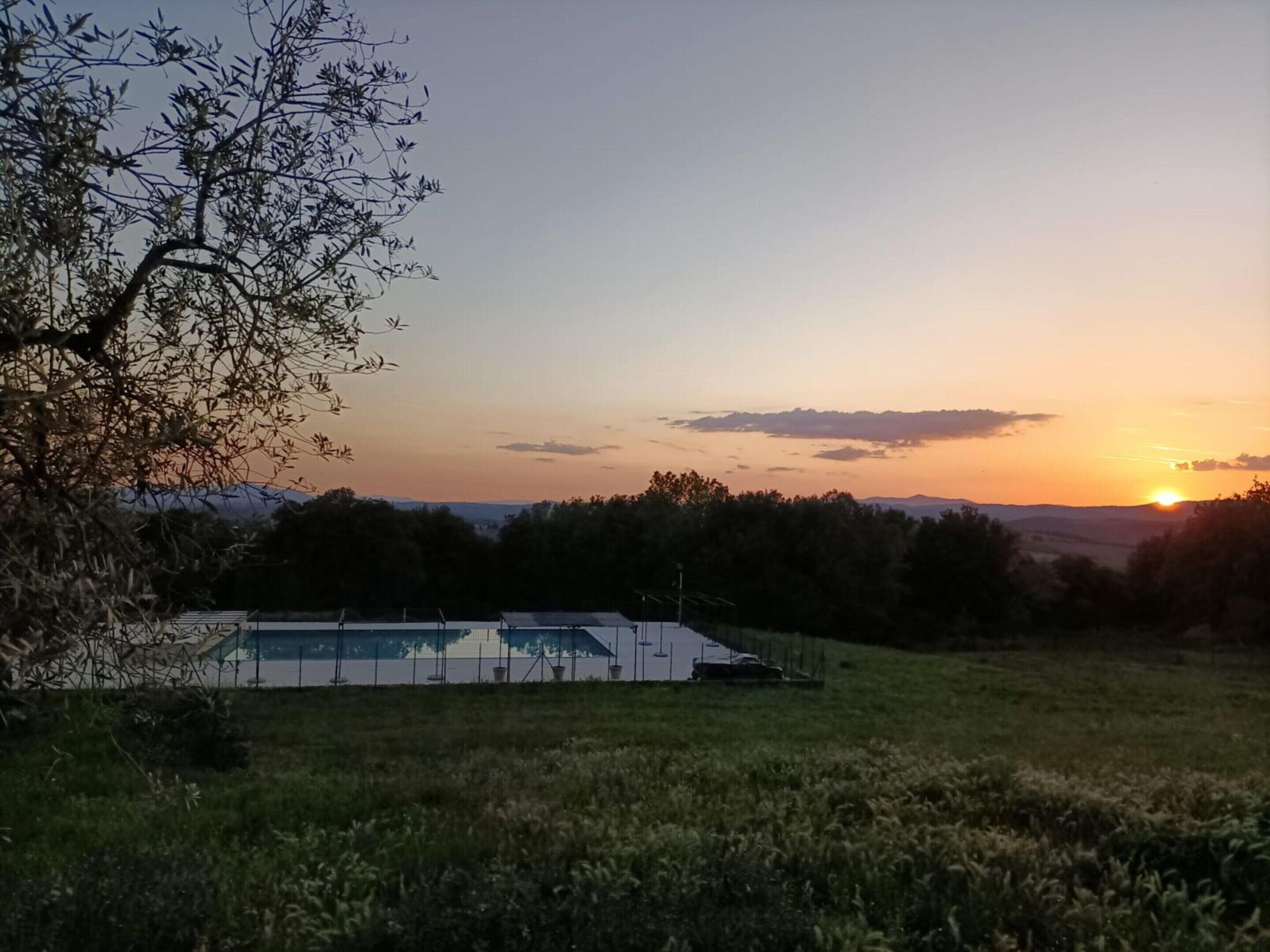 A swimming pool with a view of the sunset and mountains in the background.
