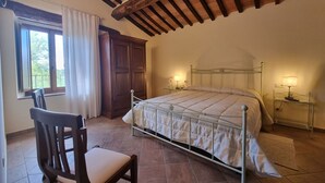 A bedroom with a bed, a chair, a wardrobe, and a window. - Tasteful Countryside Stay (Montalcino)