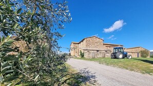 A rural road leading to a stone building with a blue tractor parked nearby. - Tasteful Countryside Stay (Montalcino)