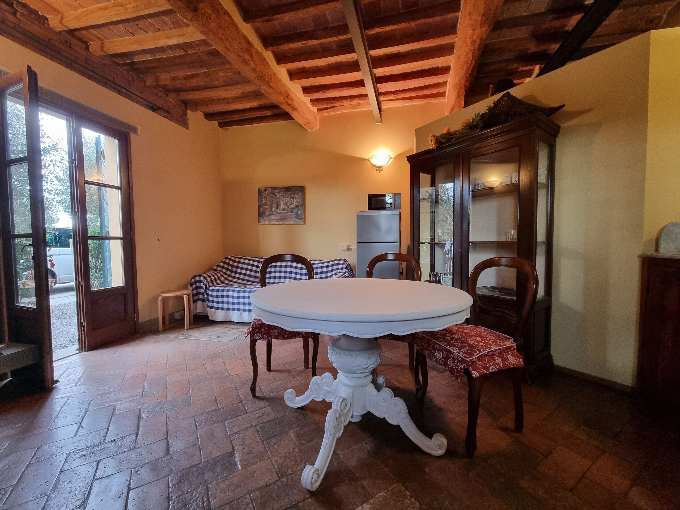A dining area with a round table, chairs, a sofa, and a cabinet.