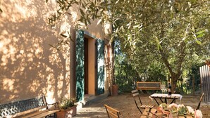 An outdoor patio with wooden tables and benches, surrounded by trees and a building with a lattice window. - Farmhouse in Tuscany With Pool & Near Montecastello (Pontedera)