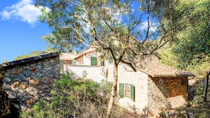 A stone house with a tiled roof, surrounded by trees and vegetation. - Tuscany Villa With Terrace (Orbetello)