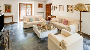 A spacious living room with two cream-colored sofas, a coffee table, and a television. - Tuscany Villa With Terrace (Orbetello)