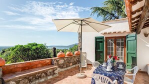 A patio with a table set for two, a large umbrella, and a view of the sea. - Tuscany Villa With Terrace (Orbetello)