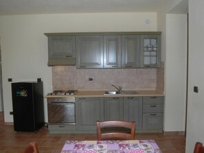 Kitchen features an oven, stovetop with four burners, and a sink with a faucet.
