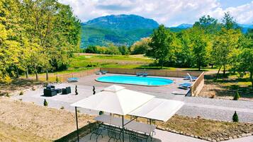 Relax by the oval-shaped pool surrounded by a deck and shaded patio area.