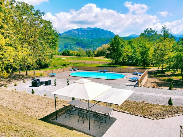 Relax by the oval-shaped pool surrounded by a deck and shaded patio area.