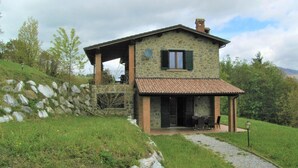 A stone house with a tiled roof, a covered porch, and a stone wall. - Holiday Home With Pool in Camporgiano (Camporgiano)
