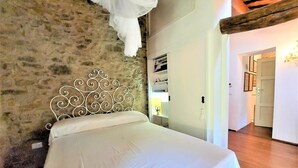 Un lit avec une tête de lit en métal décorative, un mur en pierre et un plancher en bois.