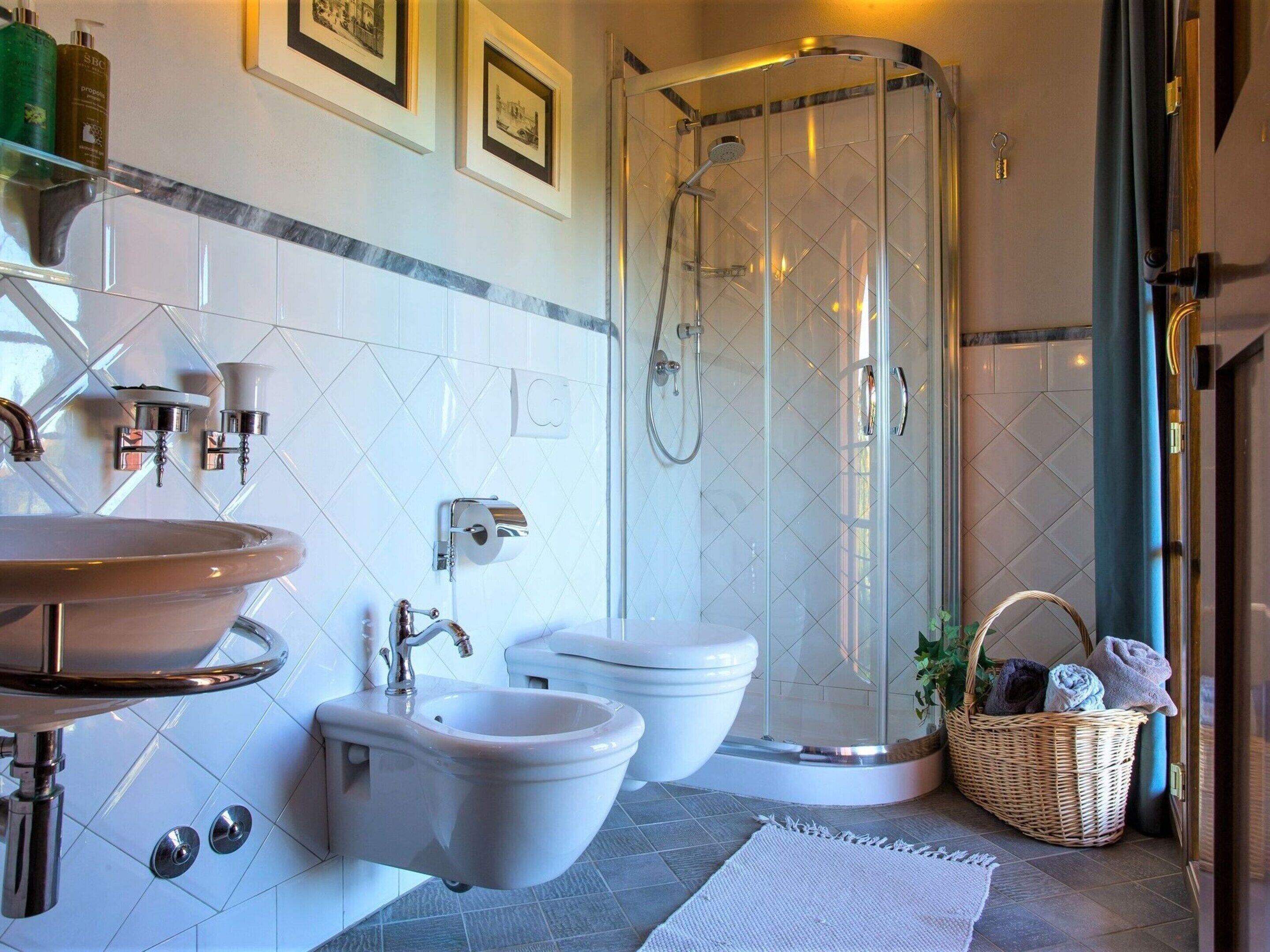 A modern bathroom with a freestanding sink, a bidet, a toilet, and a glass-enclosed shower.