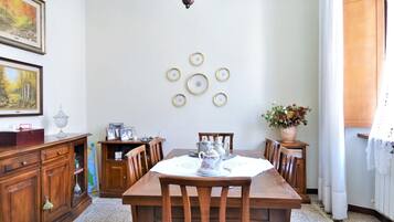 Ein Esszimmer mit Holztisch und -stühlen, einer Chandelieber, gerahmten Kunstwerken und einer Blumenvase.