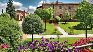 A historic building with a brick facade, a central courtyard with a pathway, and surrounding greenery. - Scenic Tuscan Mansion (Montepulciano)