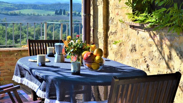 A table set outdoors with a view of a rural landscape. - Apartment in Tuscany With Stunning Views (Asciano)