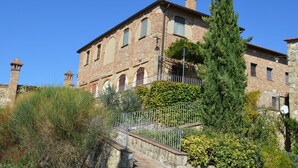 A historic building with a stone facade, multiple windows, and a central chimney. - Apartment in Tuscany With Stunning Views (Asciano)