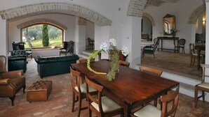 Un'ampia zona giorno con un tavolo da pranzo in legno, divani in pelle e vista sull'esterno attraverso una grande finestra.