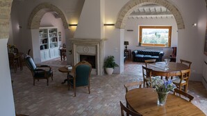 Un ampio soggiorno con camino, zona pranzo e angolo salotto accogliente con divano e poltrone in pelle.