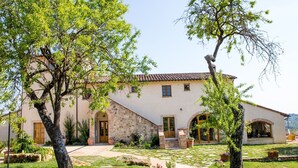 Un edificio a due piani con facciata in pietra, tetto in tegole e cortile lastricato con un sentiero in pietra.