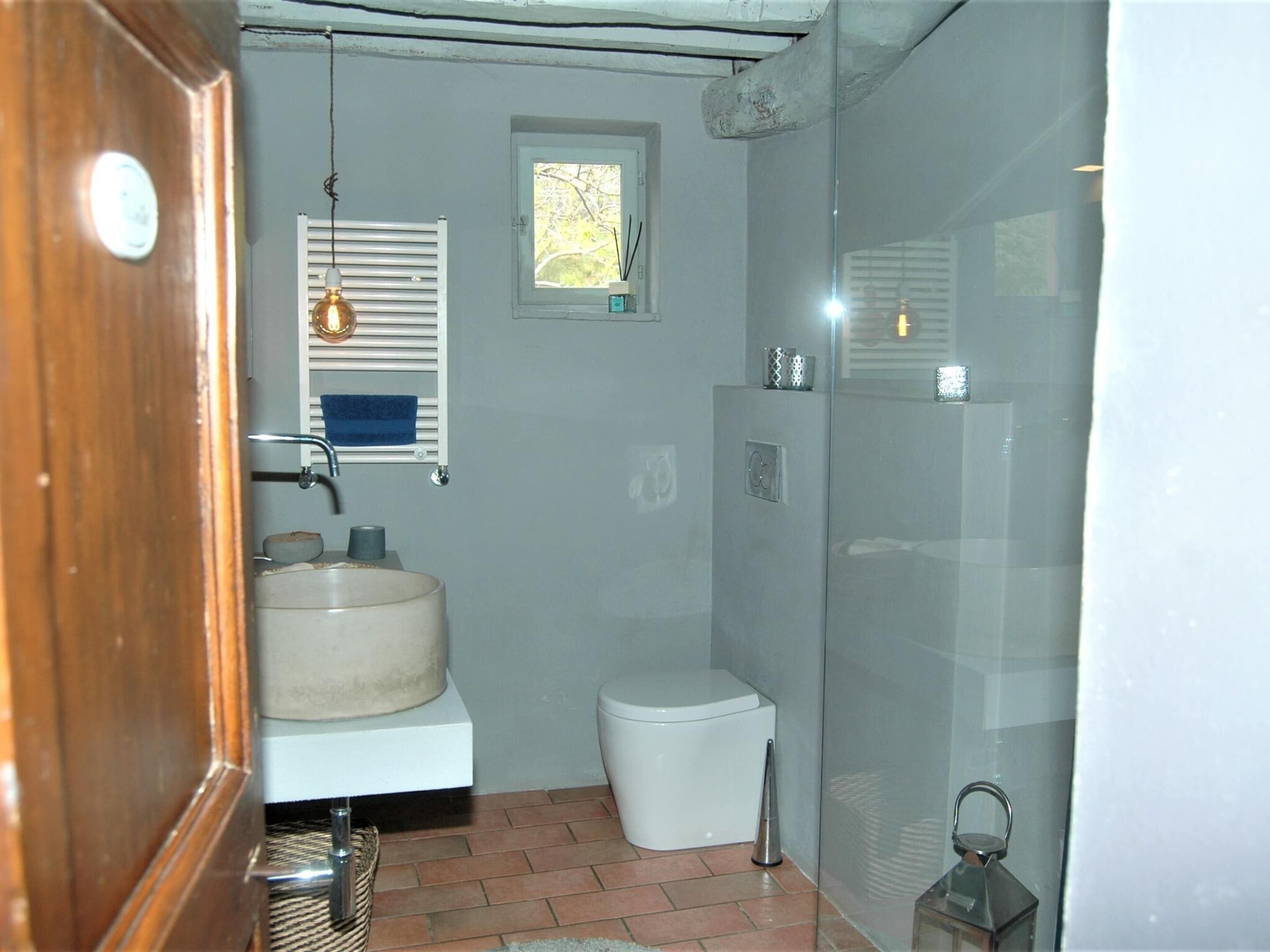 Un baño con lavamanos, inodoro y zona de ducha.
